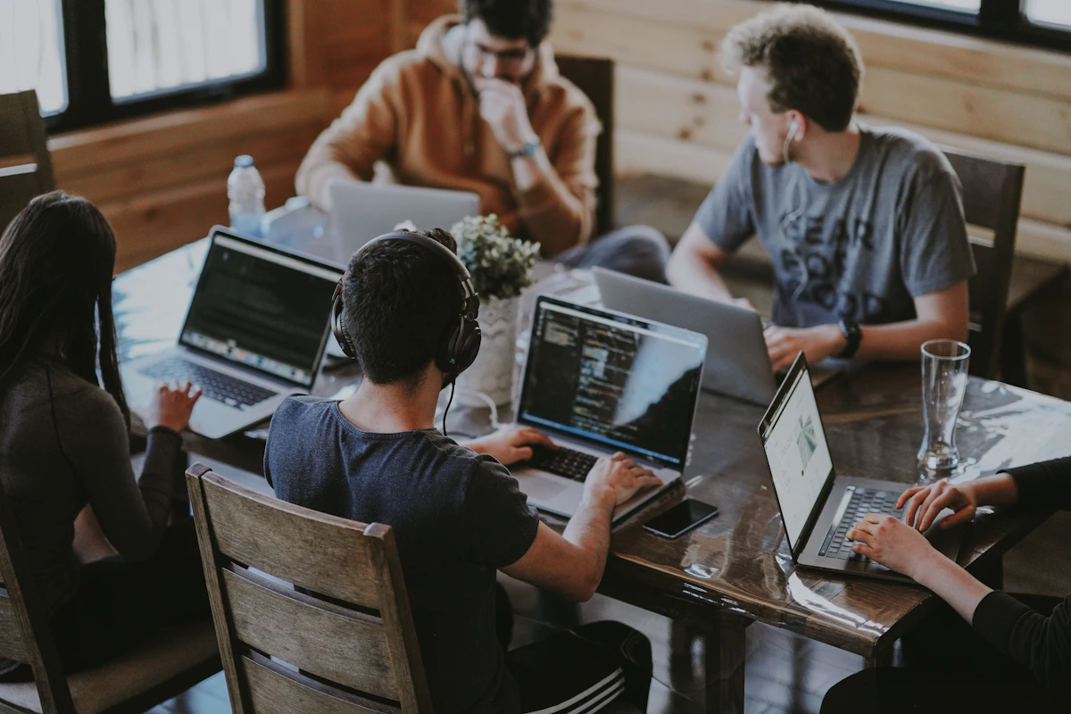 Colleagues working together around laptops at a shared table