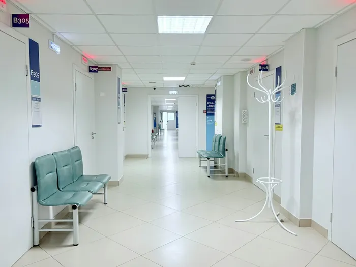Hospital corridor with teal waiting chairs and consultation room doors