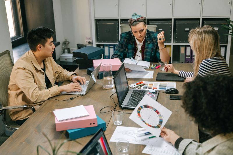 Stock photograph of colleagues planning a project around a table with laptops and documents.